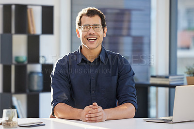 Buy stock photo Shot of a handsome young businessman sitting alone in his office during the day