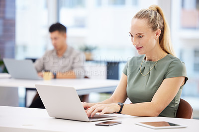 Buy stock photo Shot of an attractive young businesswoman sitting in the office and using her laptop