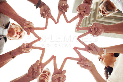 Buy stock photo Low angle shot of a group of unrecognisable people making a peace sign with their fingers to create a star shape together