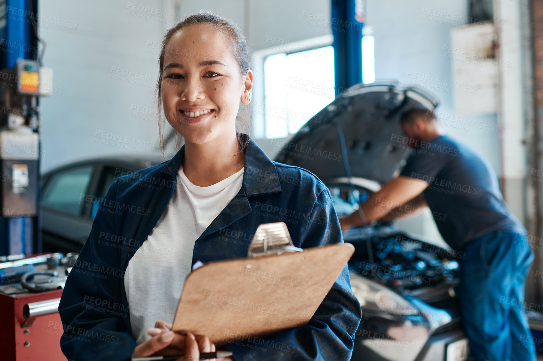 Buy stock photo Shot of a female mechanic holding a clipboard while working in an auto repair shop