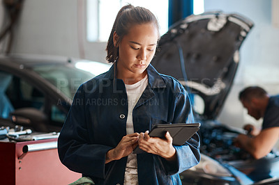 Buy stock photo Shot of a female mechanic using a digital tablet while working in an auto repair shop