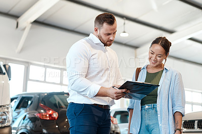 Buy stock photo Shot of a car salesman going over paperwork with his customer