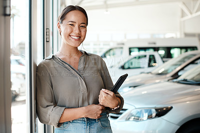 Buy stock photo Shot of a woman using her digital tablet in a car dealership