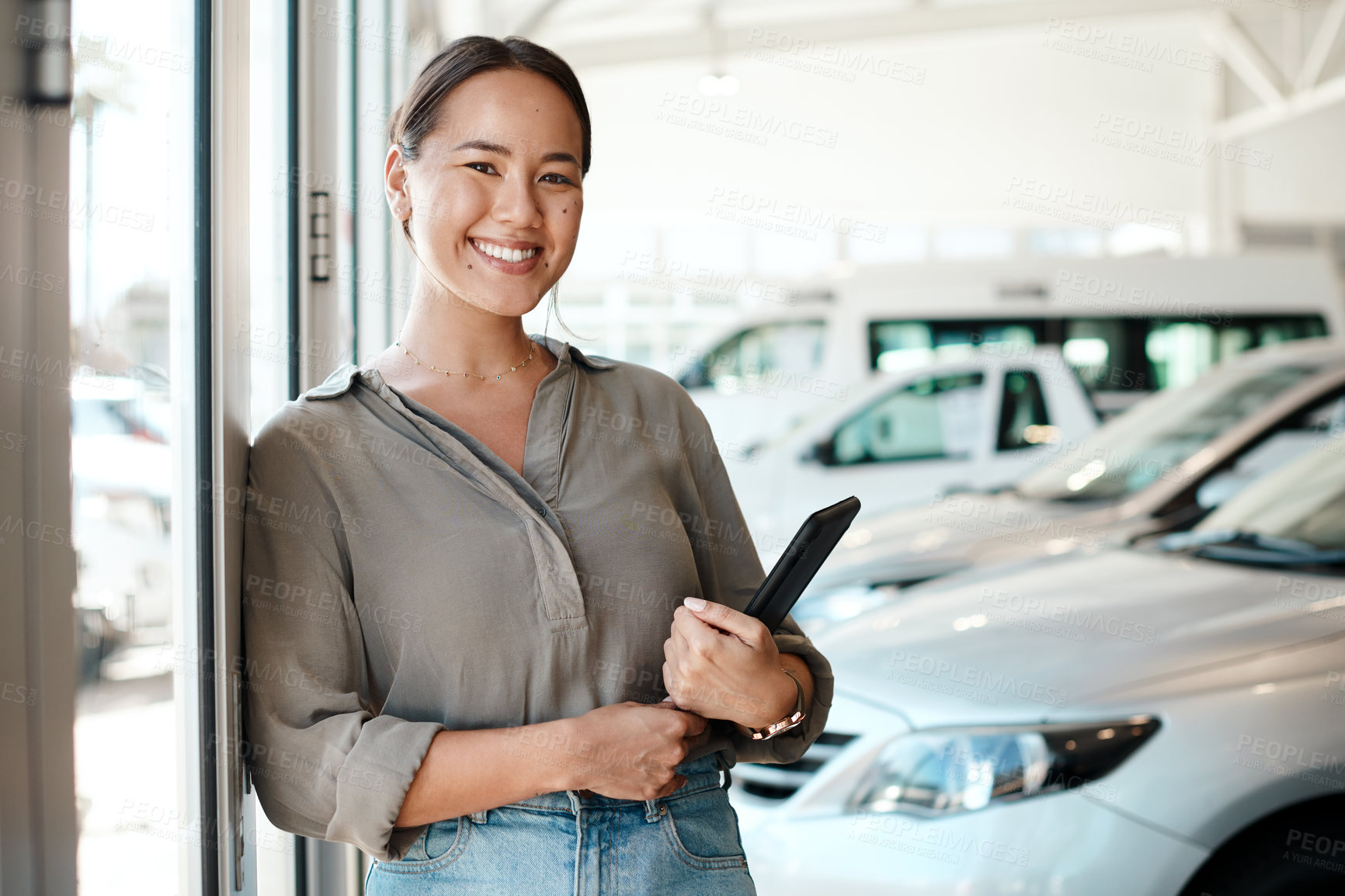 Buy stock photo Shot of a woman using her digital tablet in a car dealership