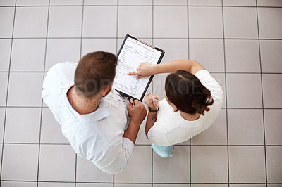 Buy stock photo Shot of a customer reading over paperwork with her salesman