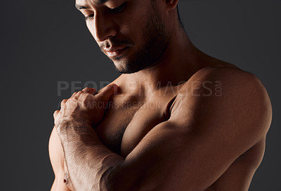 Buy stock photo Shot of a handsome young man standing alone and posing shirtless in the studio