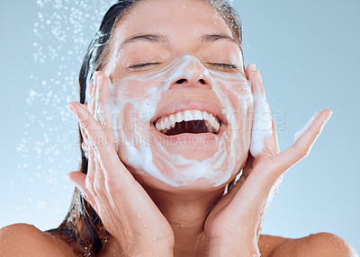 Buy stock photo Woman, facial and soap in shower for skincare hygiene, wash or clean against a blue studio background. Happy, splash and model person for wellness of face, healthy treatment by water or cosmetics