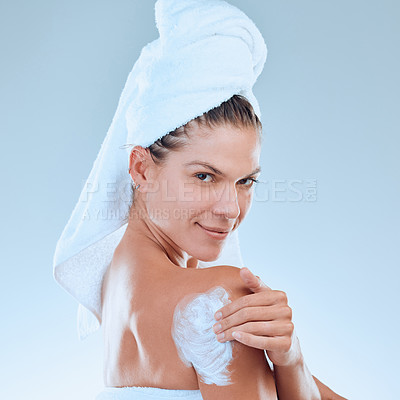 Buy stock photo Woman, lotion and apply in shoulder portrait, hydration and moisturizer or skincare on blue background. Female person, beauty and studio for skin treatment after shower, pamper routine and sunscreen