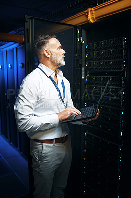 Buy stock photo Shot of a mature man using a laptop while working in a server room