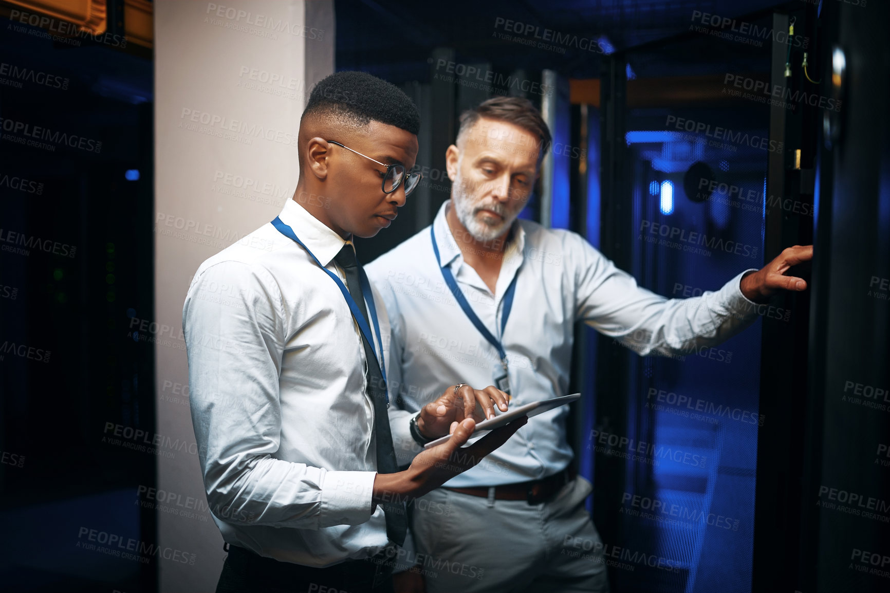 Buy stock photo Shot of two technicians using a digital tablet while working in a server room