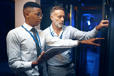 Buy stock photo Shot of two technicians using a digital tablet while working in a server room