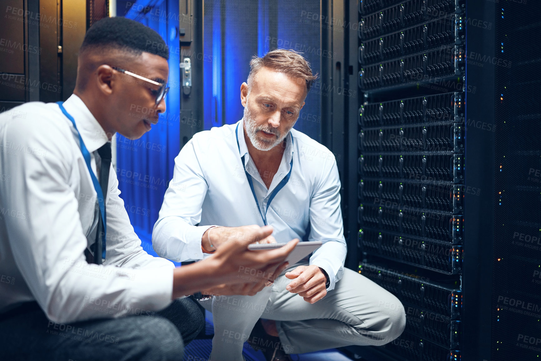 Buy stock photo Shot of two technicians using a digital tablet while working in a server room