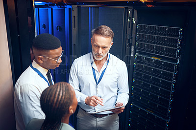 Buy stock photo Shot of a group of technicians using a digital tablet while working together in a server room