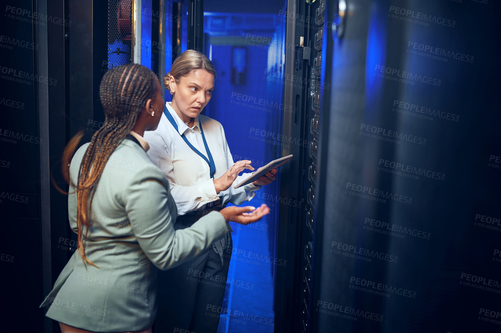 Buy stock photo Shot of two technicians using a digital tablet while working in a server room