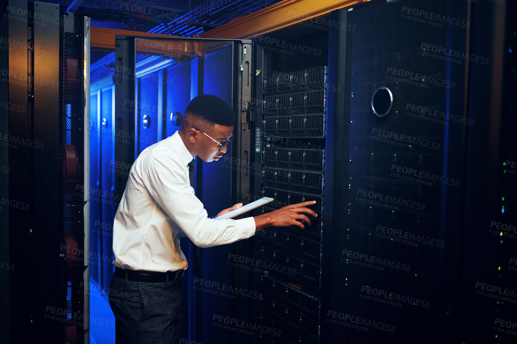 Buy stock photo Shot of a young man using a digital tablet while working in a server room