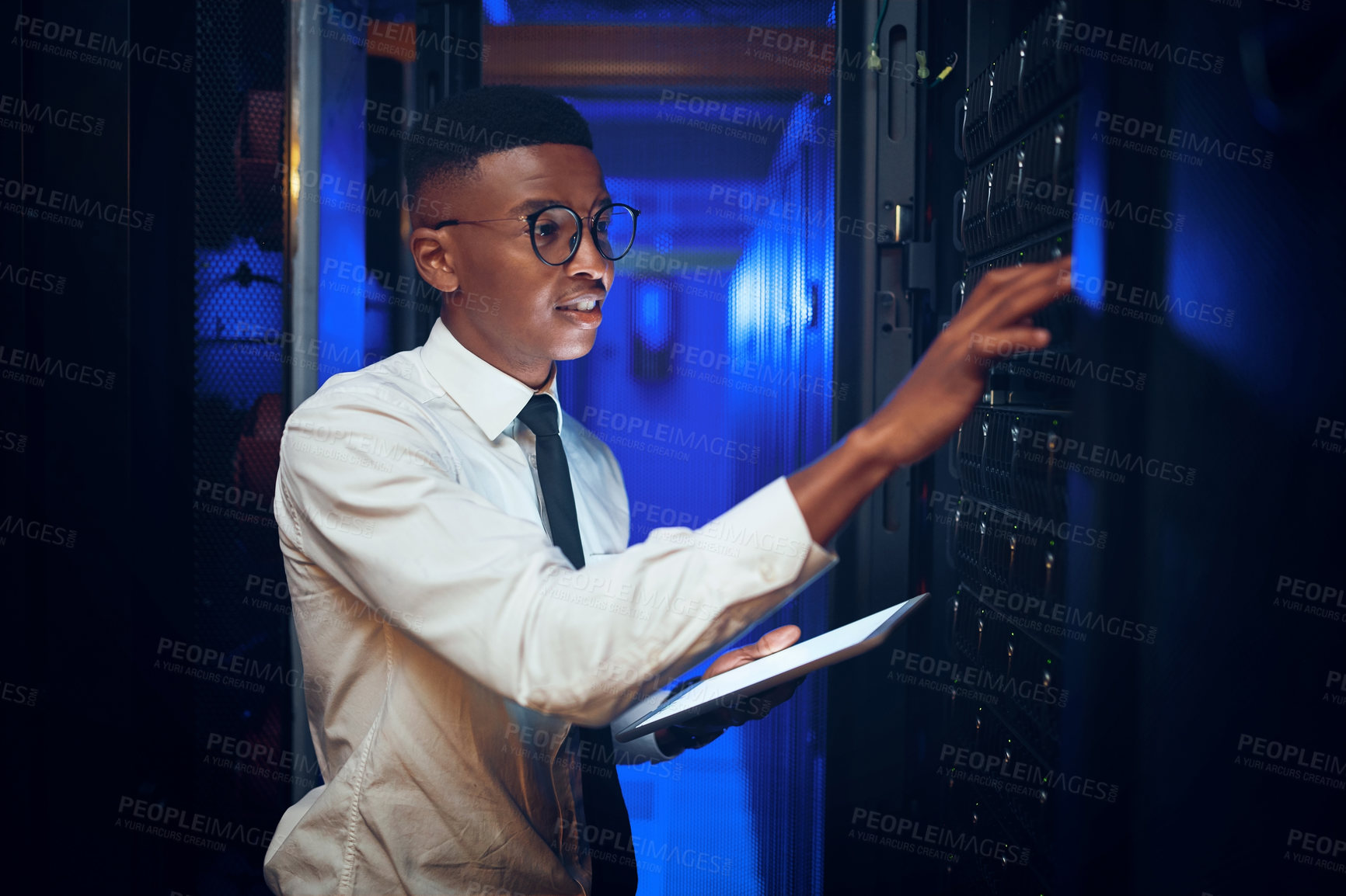 Buy stock photo Shot of a young man using a digital tablet while working in a server room