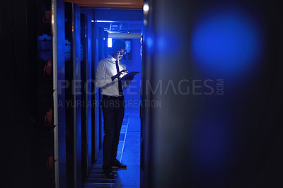 Buy stock photo Shot of a young man using a digital tablet while working in a server room