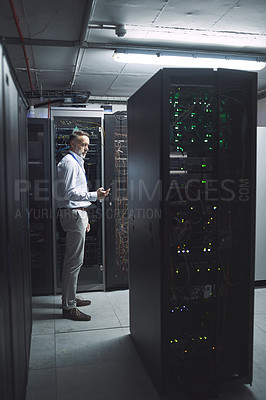 Buy stock photo Shot of a mature man using a cellphone while working in a server room