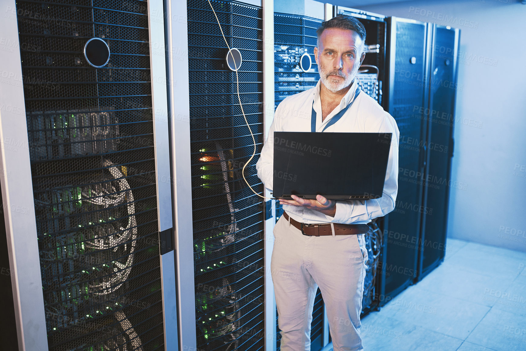 Buy stock photo Portrait of a mature man using a laptop while working in a server room