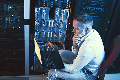 Buy stock photo Shot of a mature man looking thoughtful while using a laptop in a server room