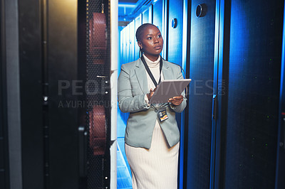 Buy stock photo Shot of a young IT specialist standing alone in the server room and using a digital tablet