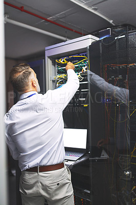 Buy stock photo Rearview shot of a mature man using a laptop while working in a server room