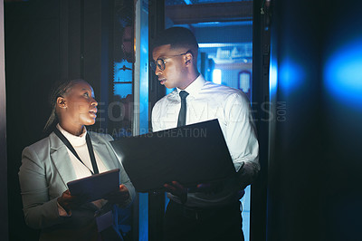 Buy stock photo Shot of two young IT specialists standing in the server room and having a discussion while using a technology