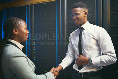 Buy stock photo Shot of two young IT specialists standing in the server room together and shaking hands