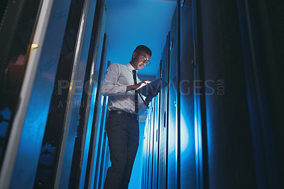 Buy stock photo Shot of a young IT specialist standing alone in the server room and using a digital tablet