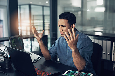 Buy stock photo Shot of a young frustrated man making hopeless gestures while using a laptop in a modern office