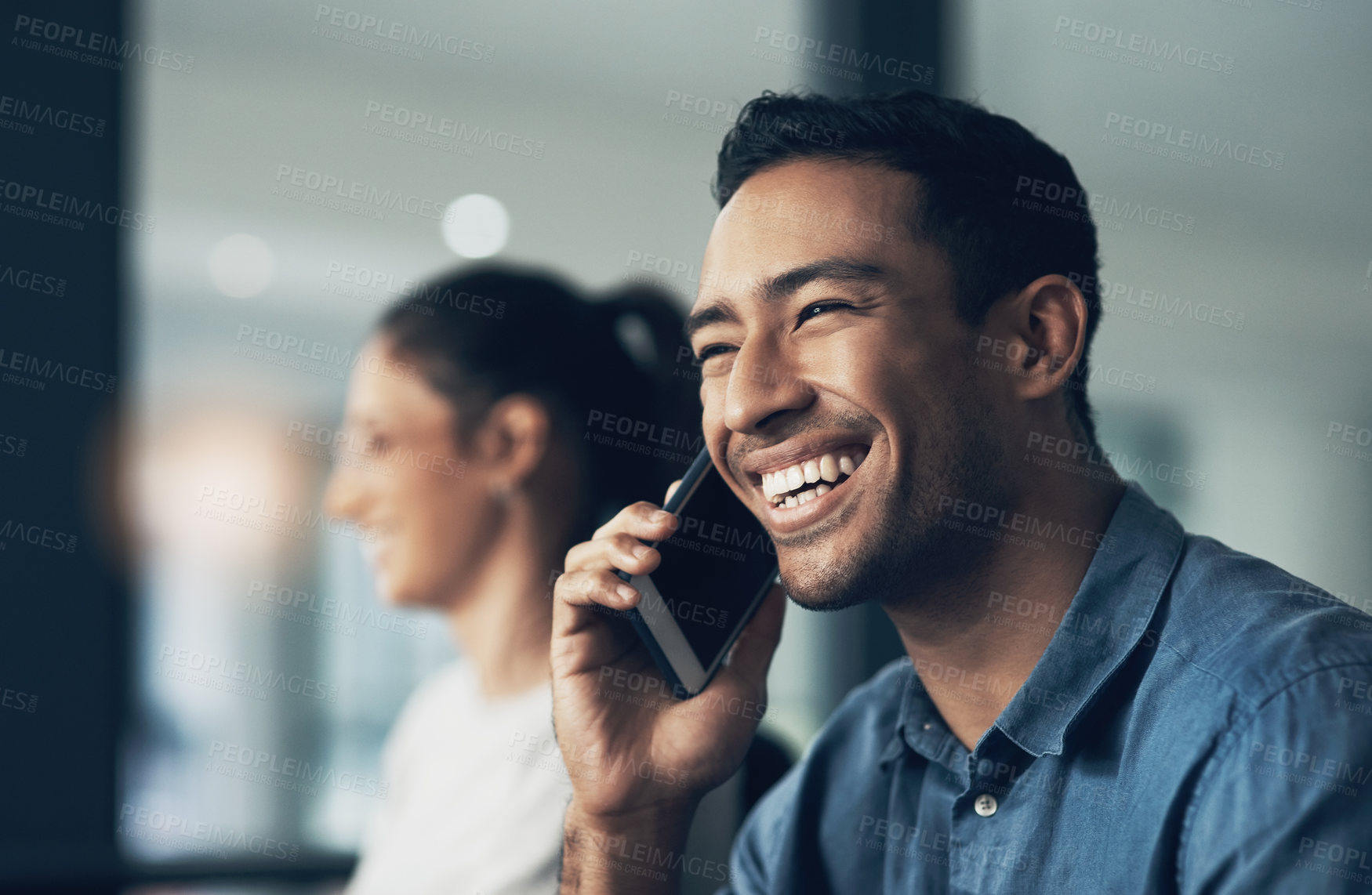 Buy stock photo Shot of a happy young man chatting on a cellphone in a modern office