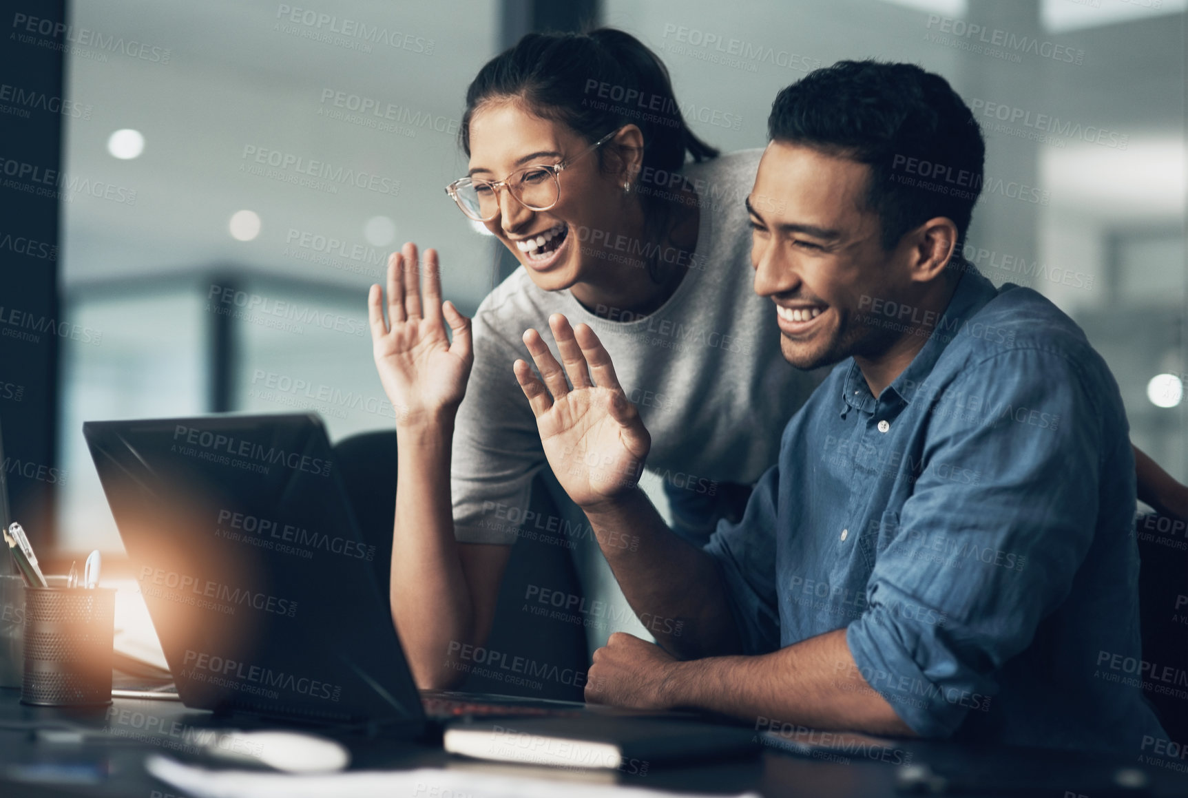 Buy stock photo Shot of two young workers using a laptop for a business meeting in a modern office