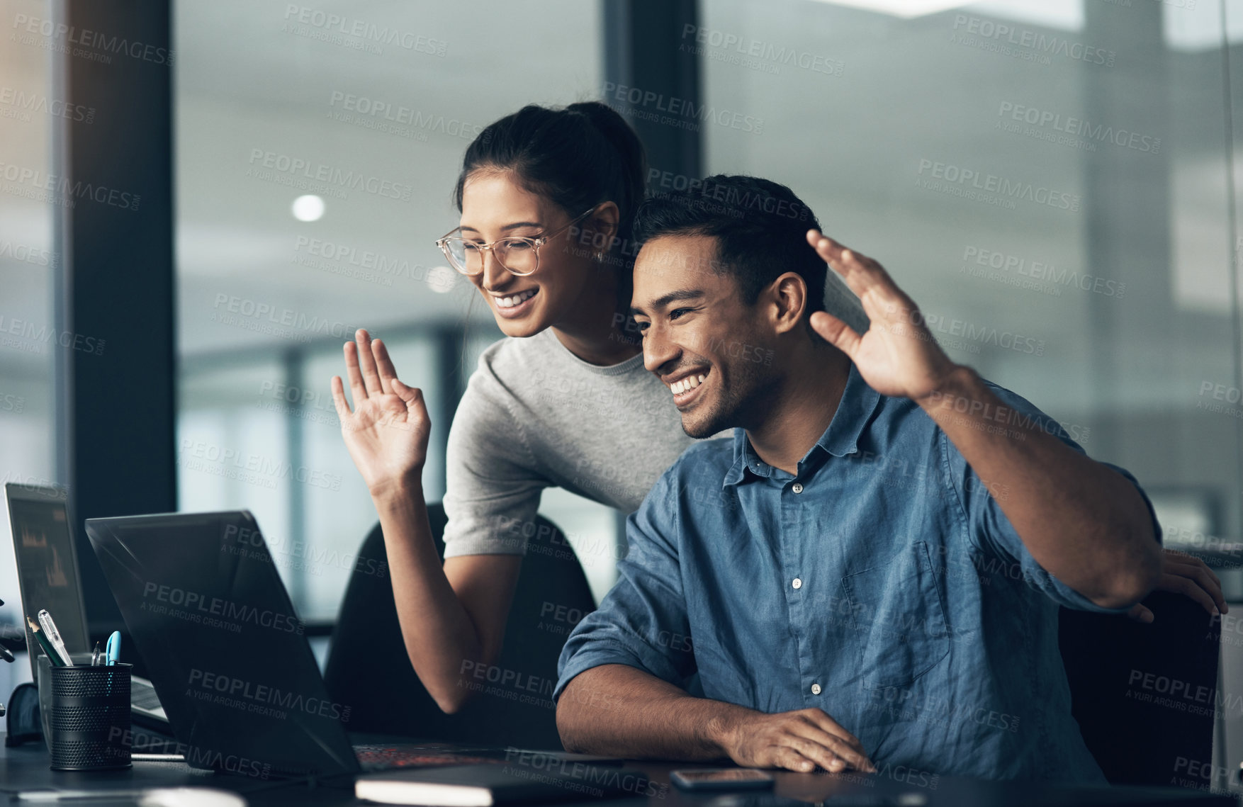 Buy stock photo Shot of two young workers using a laptop for a business meeting in a modern office