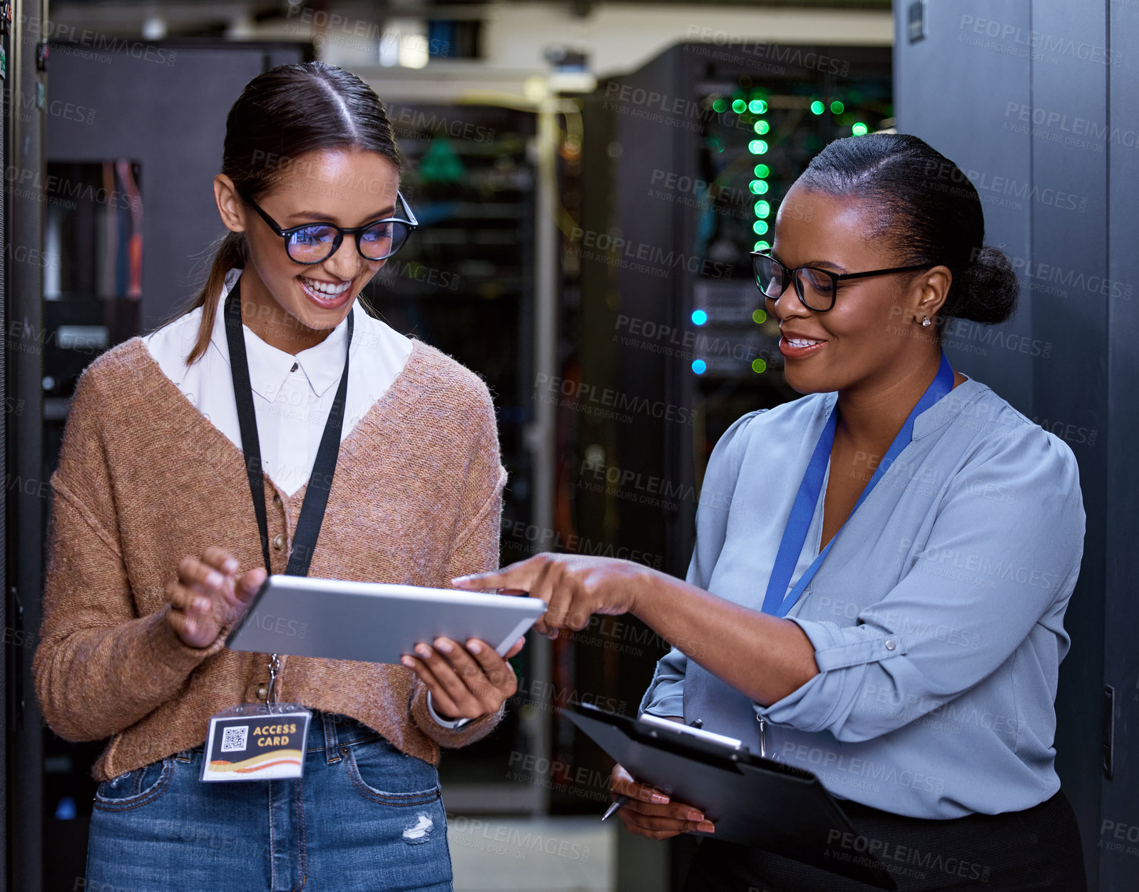 Buy stock photo Cropped shot of two attractive young female computer programmers working together in a server room