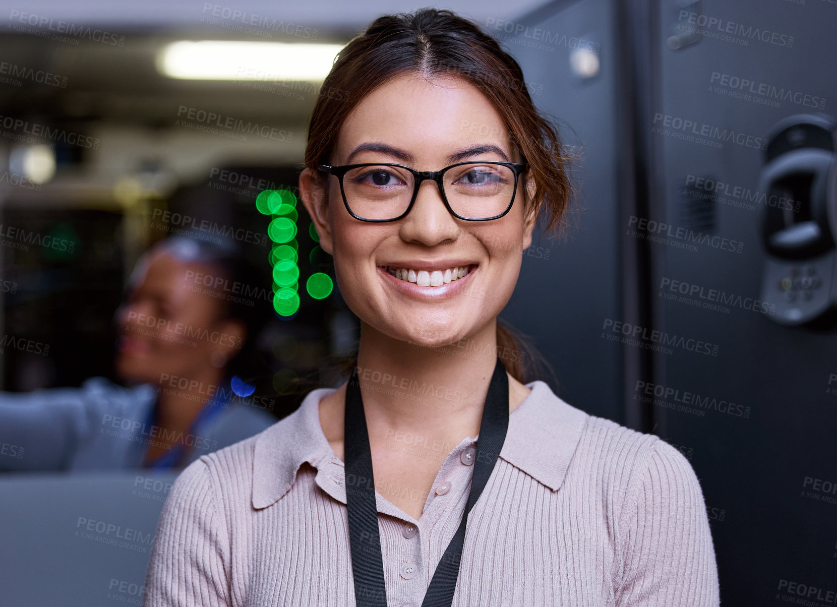 Buy stock photo Cropped portrait of an attractive young female programmer working in a server room with her colleague in the background