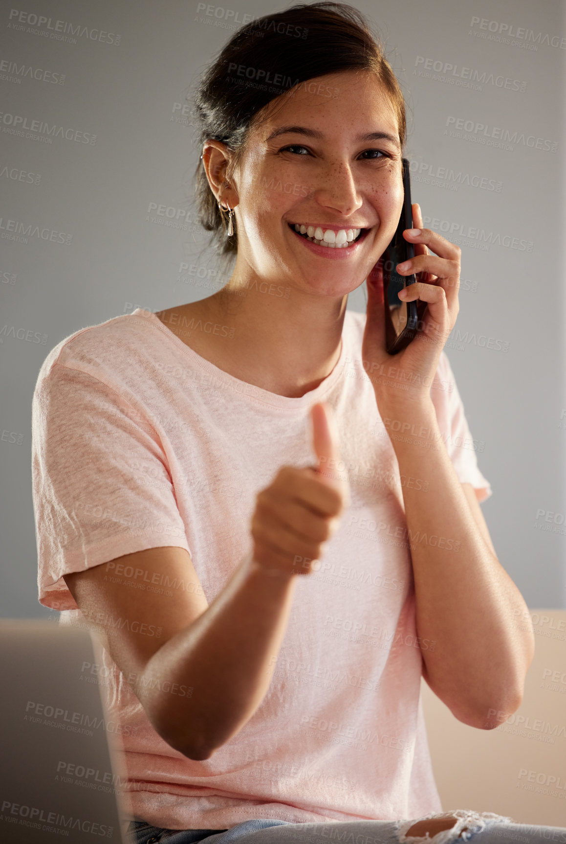 Buy stock photo Shot of a young woman giving the thumbs up while making a call using her smartphone