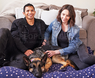 Buy stock photo Shot of a young couple sitting in their living room with their German Shepherd during a day at home