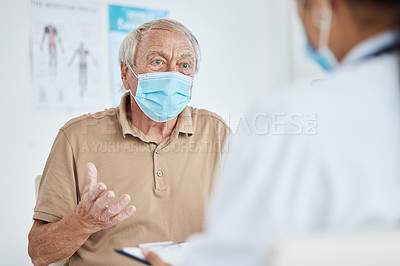 Buy stock photo Shot of a senior man sitting with his doctor and wearing a face mask during his consult in the clinic