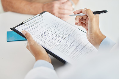 Buy stock photo Cropped shot of an unrecognizable doctor sitting with her patient and reading paperwork during a consult in the clinic