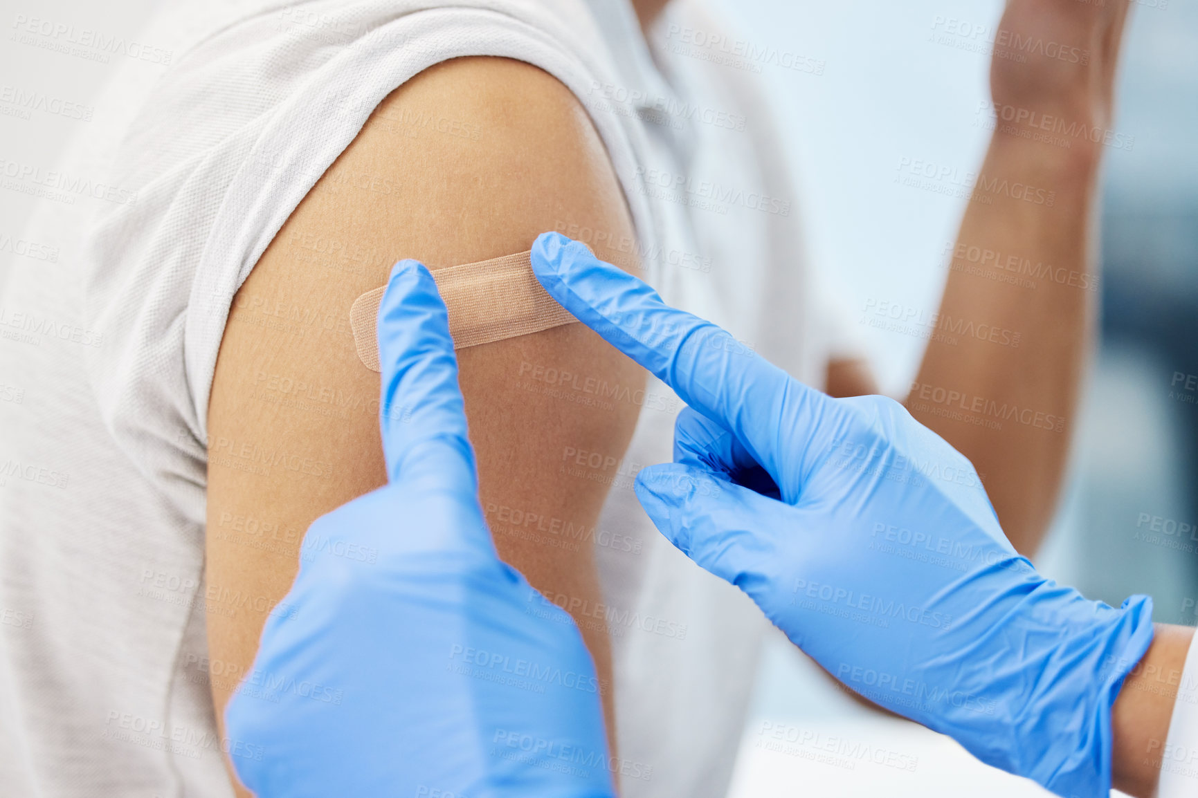 Buy stock photo Cropped shot of an unrecognizable doctor putting a band-aid on her patient after giving him the Covid vaccine