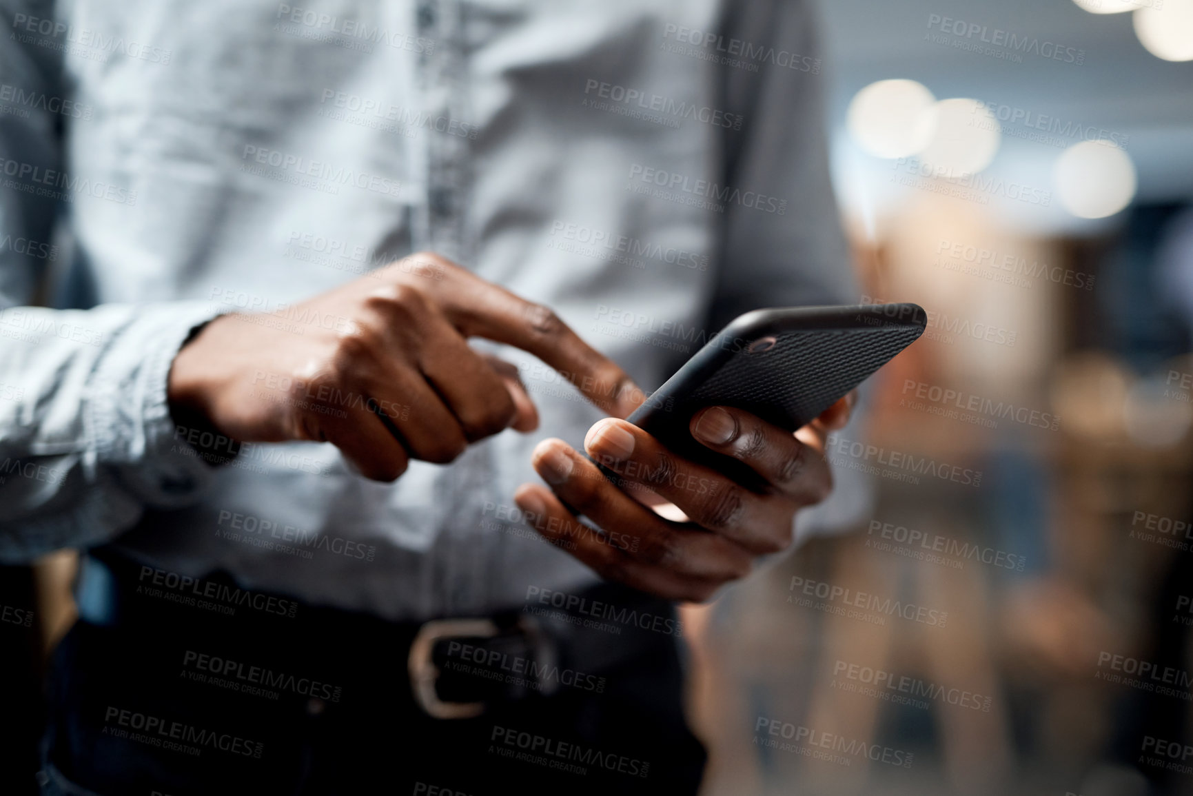 Buy stock photo Shot of an unrecognisable businessman using a smartphone in a modern office