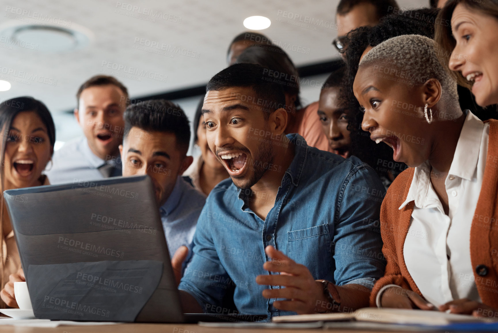 Buy stock photo Shot of a group of young businesspeople using a laptop and looking shocked in a modern office