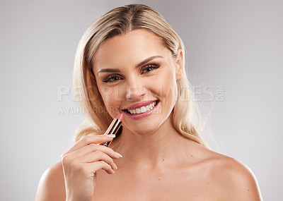 Buy stock photo Studio shot of a beautiful young woman applying lipstick against a grey background