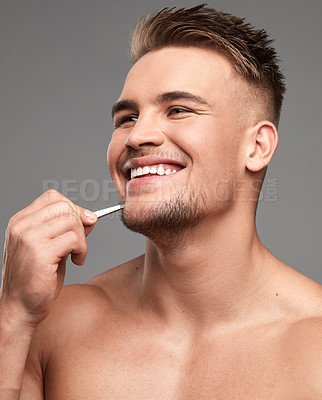 Buy stock photo Studio shot of a handsome young man plucking his beard against a grey background