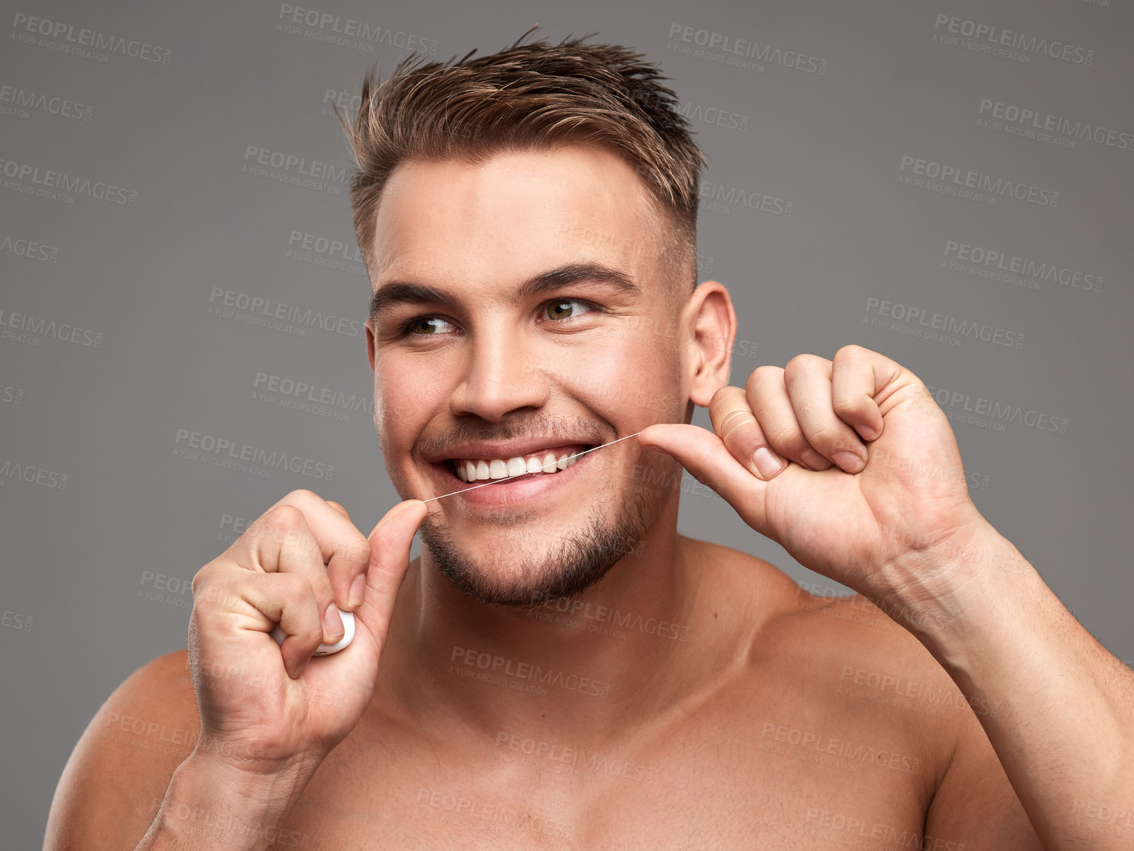 Buy stock photo Studio shot of a handsome young man flossing his teeth against a grey background