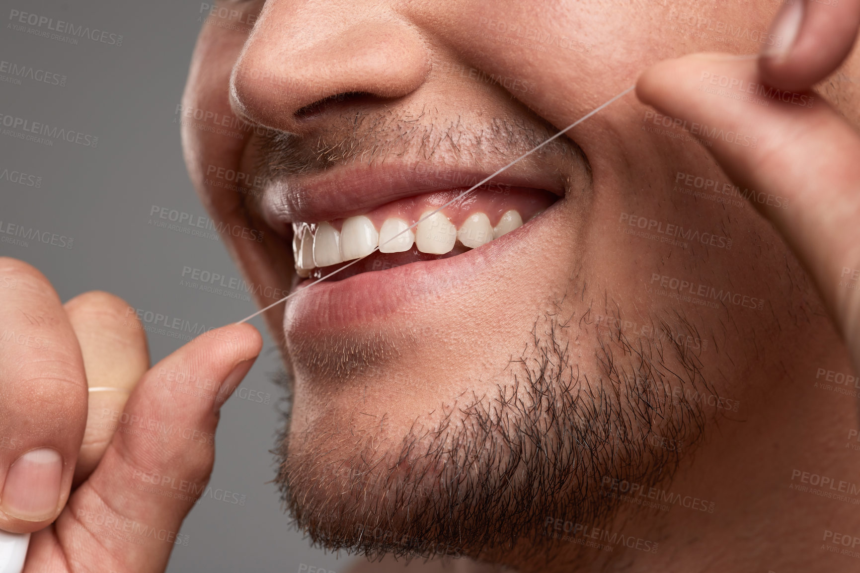 Buy stock photo Studio shot of an unrecognisable man flossing his teeth against a grey background