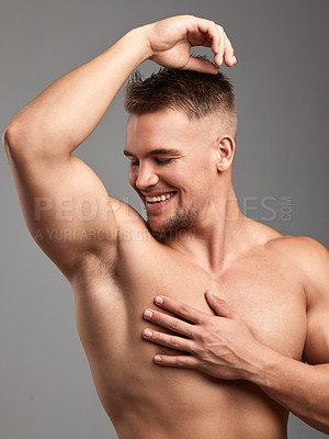 Buy stock photo Studio shot of a handsome young man smelling his armpit against a grey background