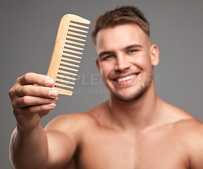 Buy stock photo Studio shot of a handsome young man holding a comb against a grey background