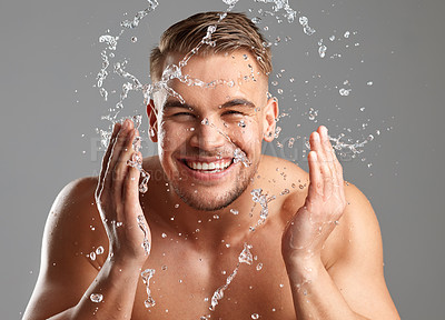 Buy stock photo Studio shot of a handsome young man washing his face against a grey background