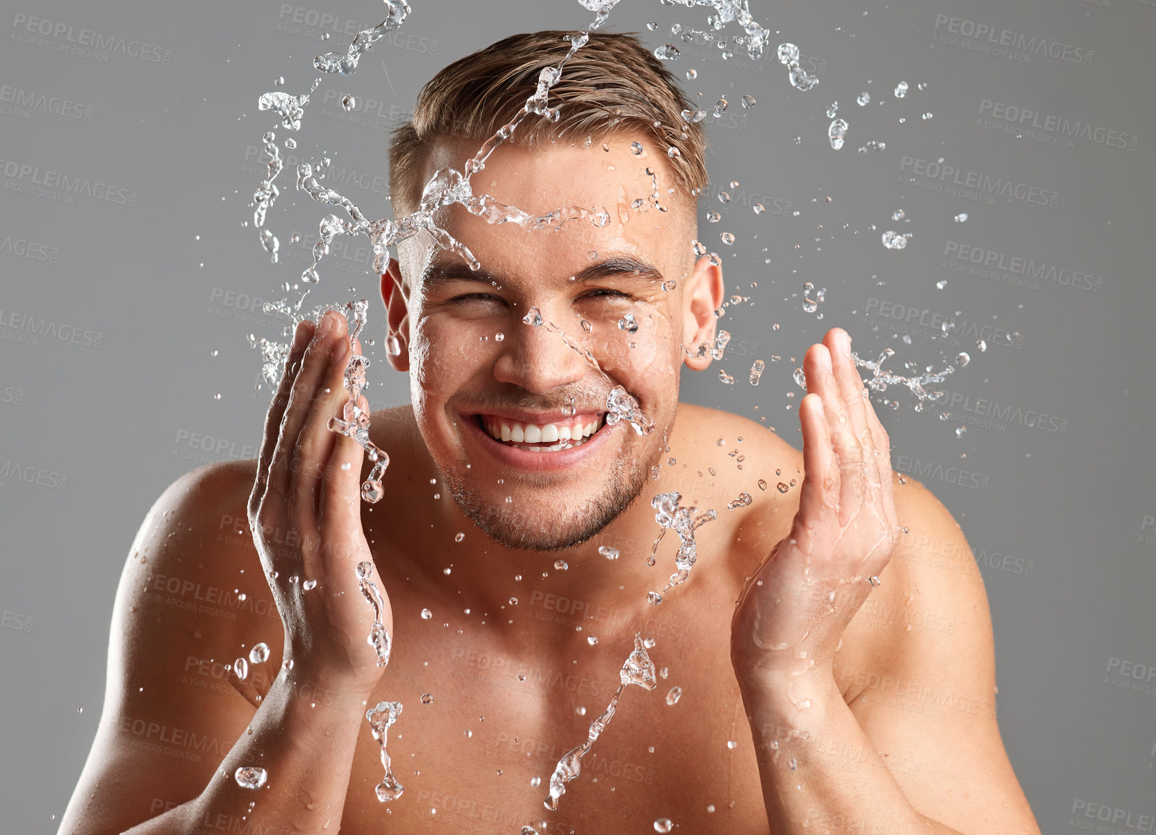 Buy stock photo Studio shot of a handsome young man washing his face against a grey background